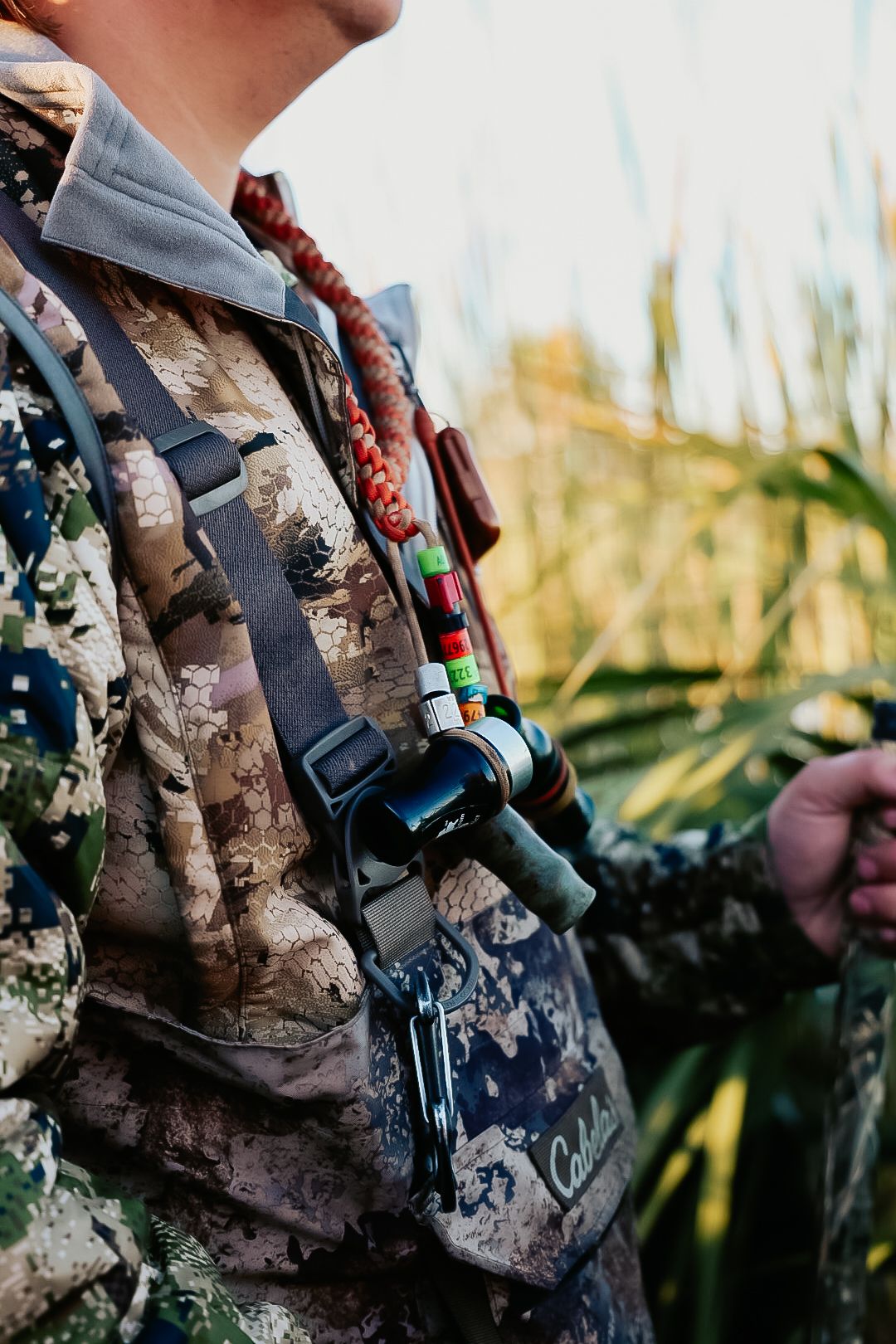 Close-up of hunter in camo gear with duck calls and equipment attached to vest.