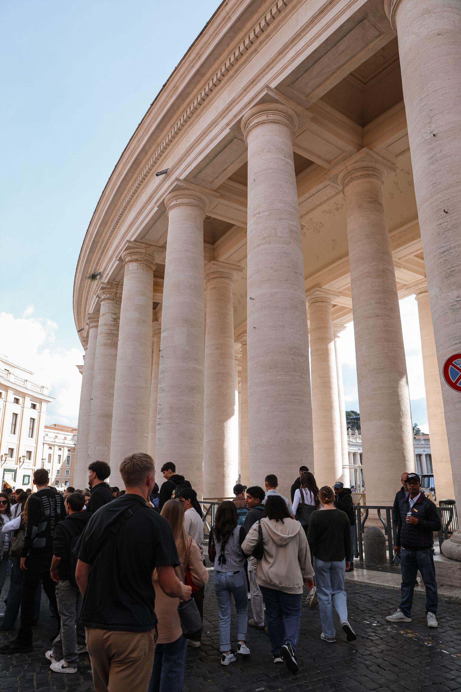 Tourists gather among the grand Doric columns of St. Peter's Square colonnade in Vatican City, Rome.