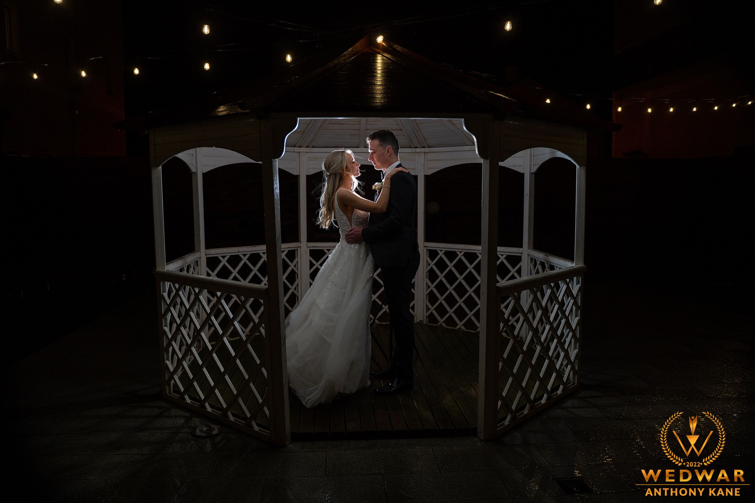 Romantic nighttime scene in a decorative gazebo with string lights overhead.