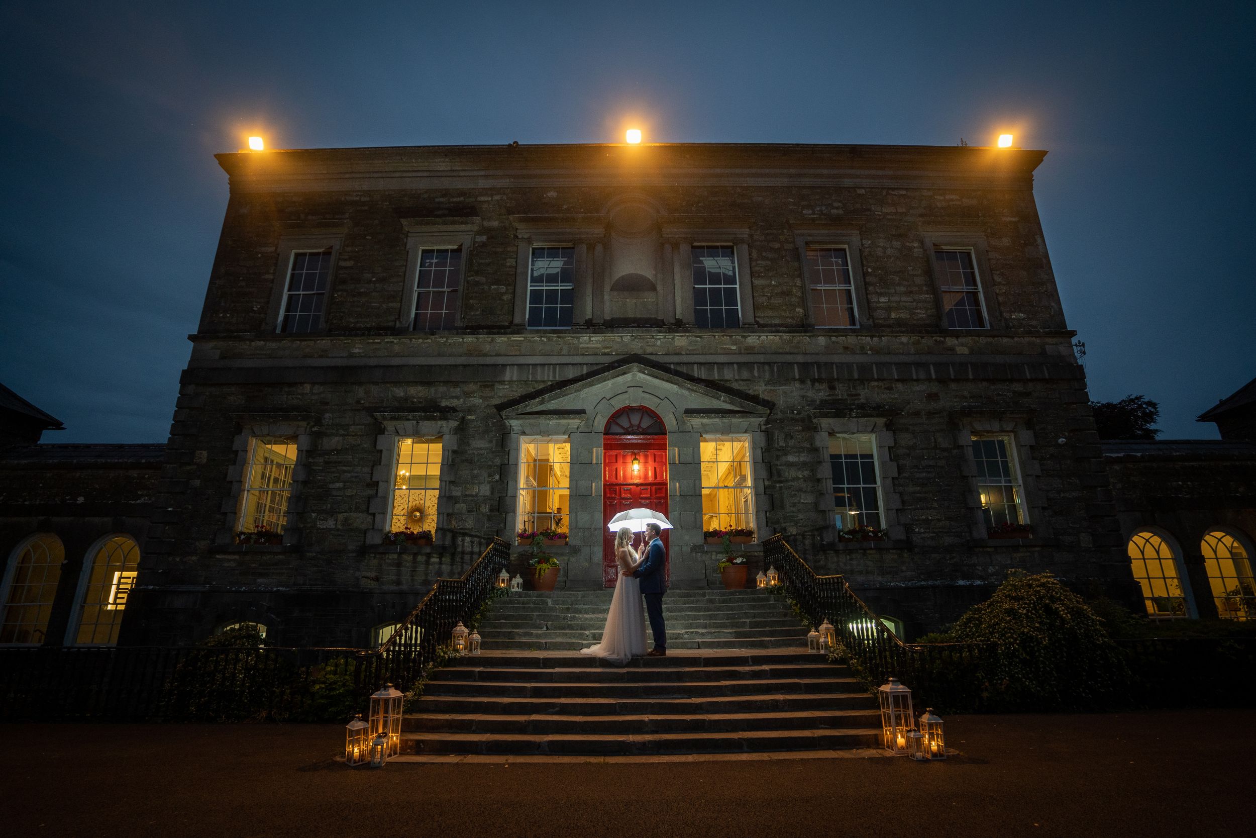 Dramatic nighttime wedding photo of illuminated stone mansion with couple silhouetted in doorway at Bellinter House Co. Meath
