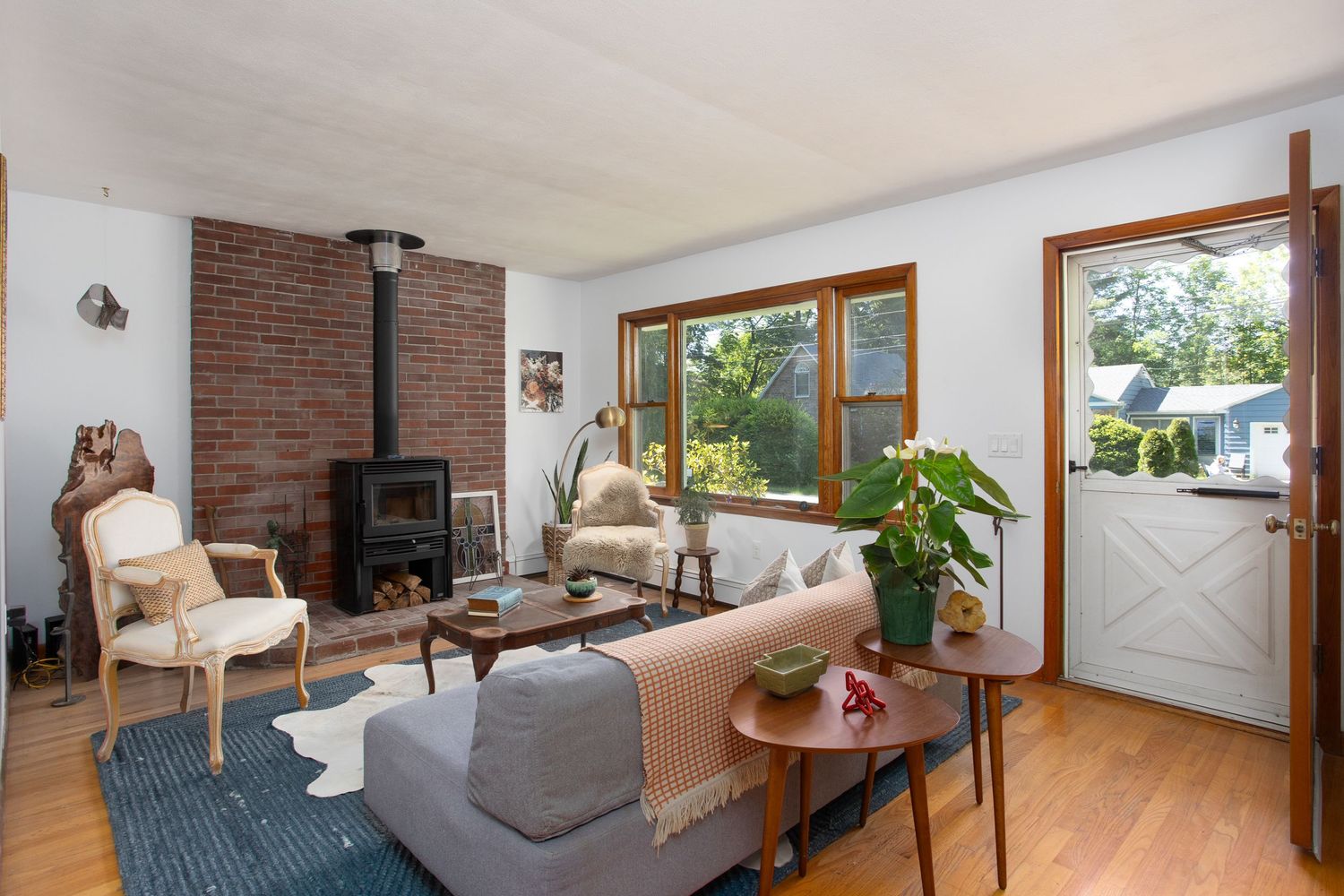 Cozy living room with brick wood-burning stove, hardwood floors, and natural light.