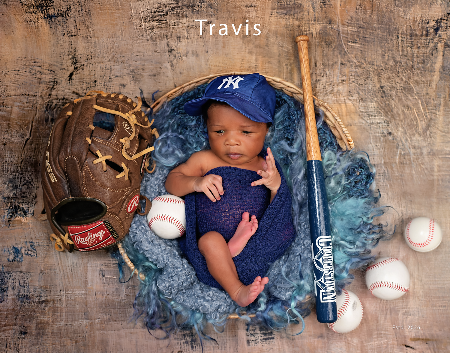 Newborn baby in a blue wrap photographed with his father’s baseball glove, bat and baseballs.