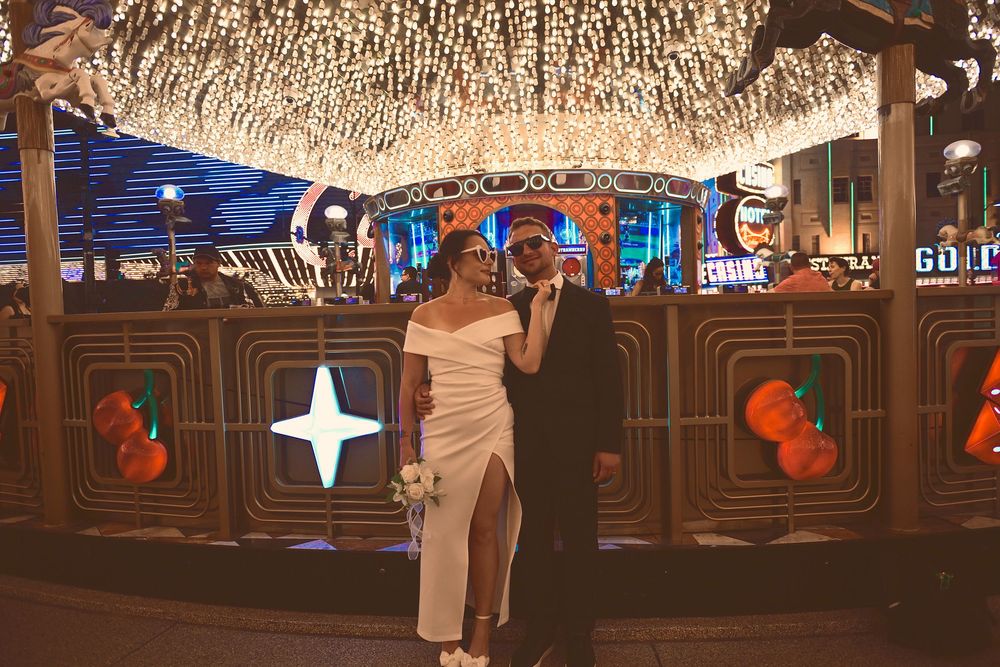 Newlywed couple posing under sparkling lights on the Las Vegas Strip in formal wedding attire.