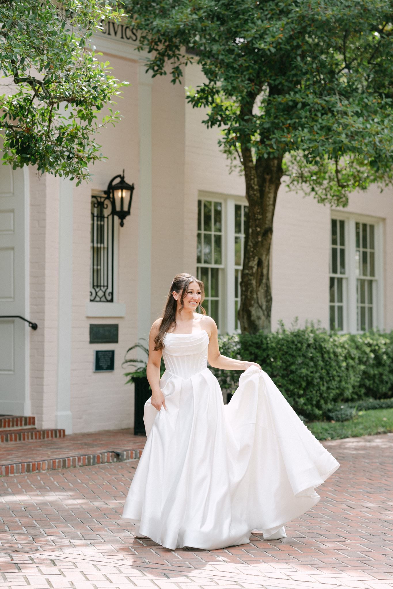 Bride walking and swaying her dress in front of the River Oaks Garden Club.