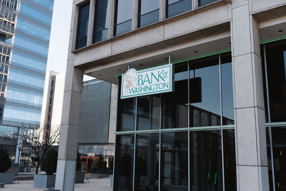 Exterior view of Bank of Washington branch entrance with green signage on a modern stone building facade.