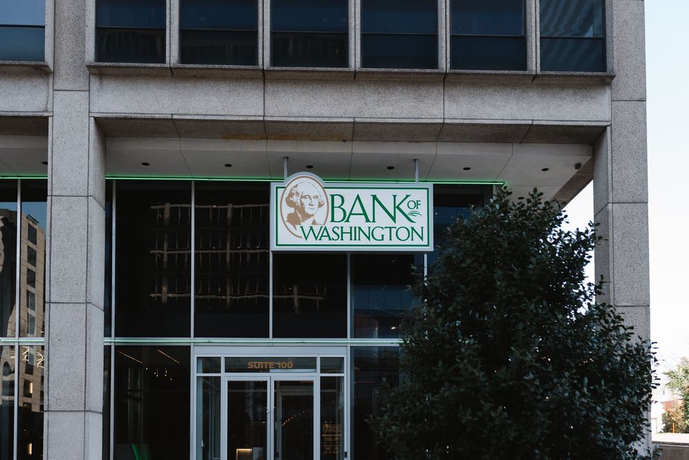 Bank of Washington building exterior featuring green logo signage above glass entrance doors on a modern urban facade.