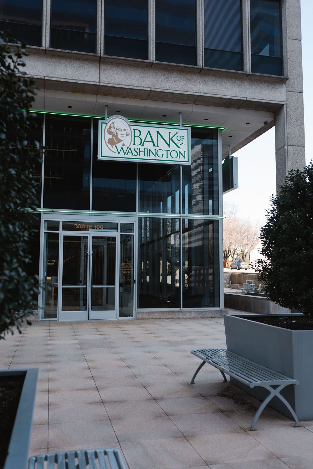 Bank of Washington building entrance with glass doors, metal bench, and green signage on modern facade.