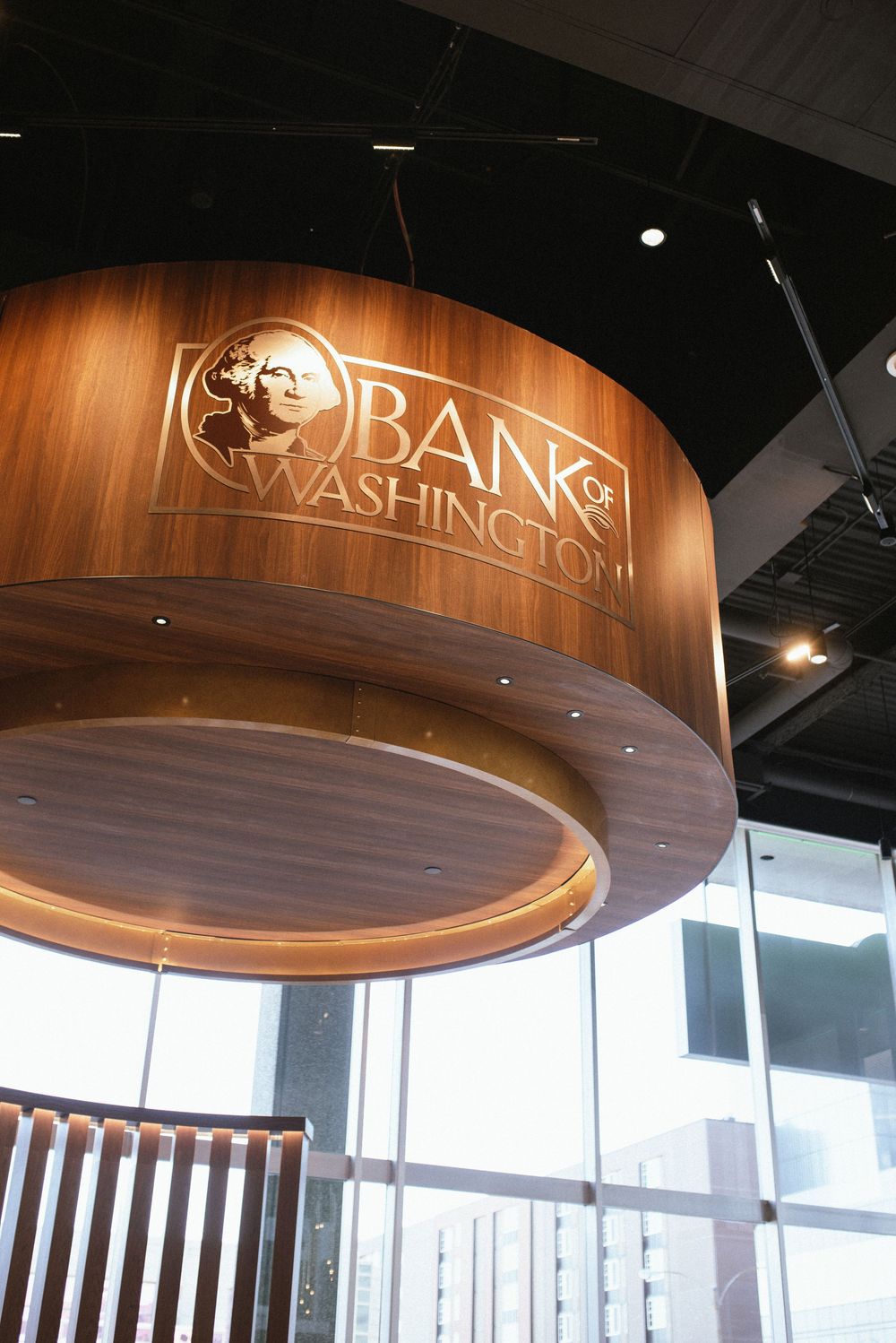Interior view of Bank of Washington branch featuring elegant wood-paneled circular desk with gold logo signage.