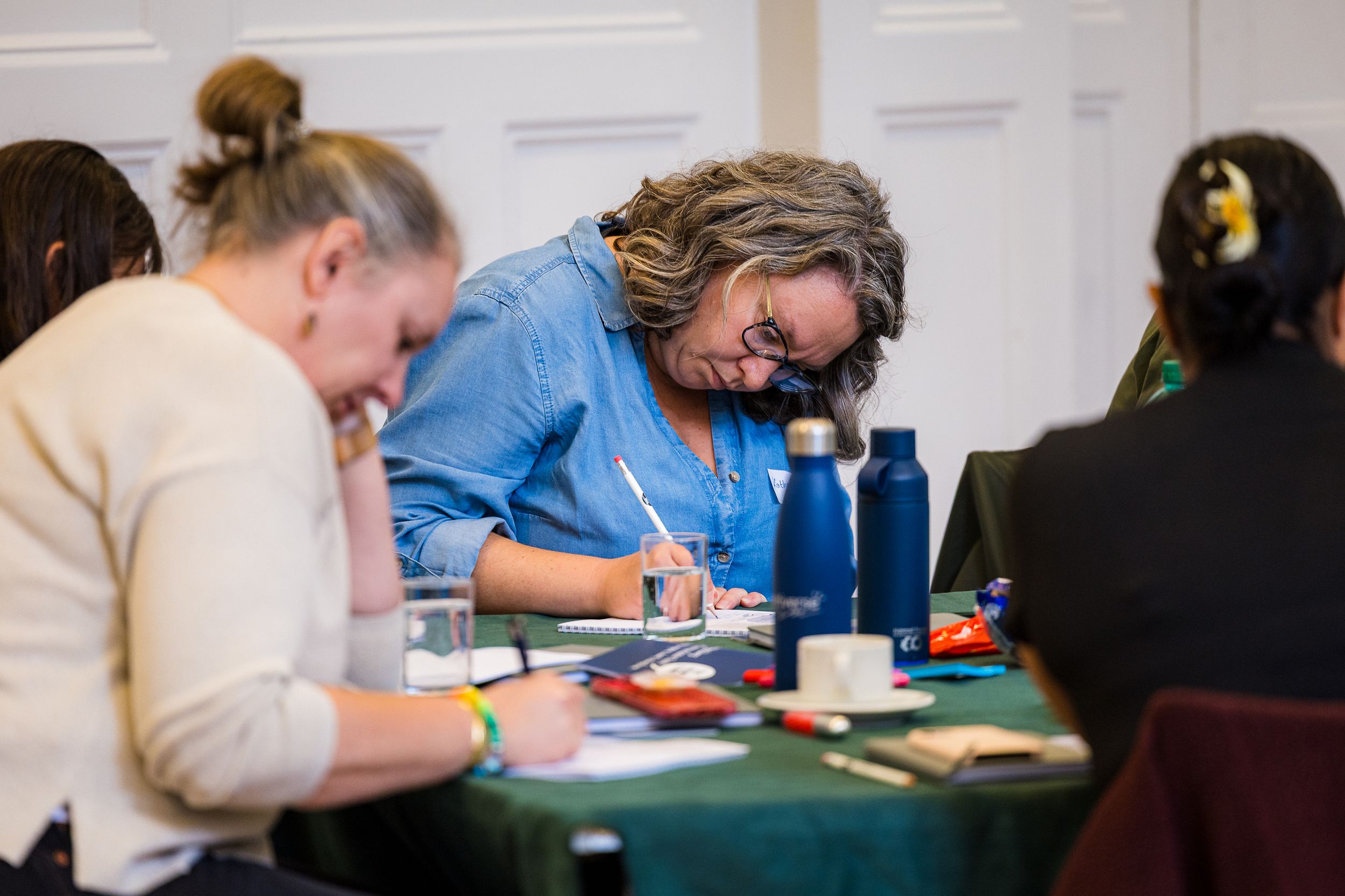 Group of professionals taking notes at a training workshop seated around a table.