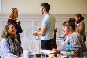 Professionals networking and conversing at a business training event in a formal venue.