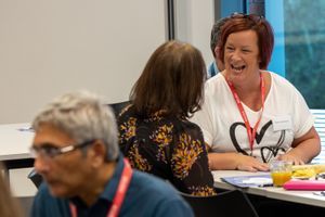Woman wearing lanyard laughing during an interactive professional development training session.