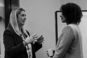 Two professional women engaged in conversation at a business networking event in black and white photo.