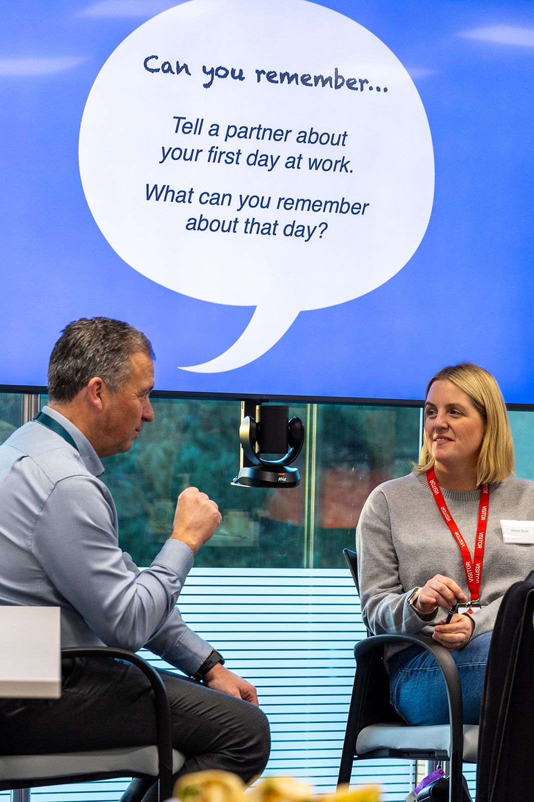 Two professionals discuss first day at work memories during interactive storytelling communication workshop.