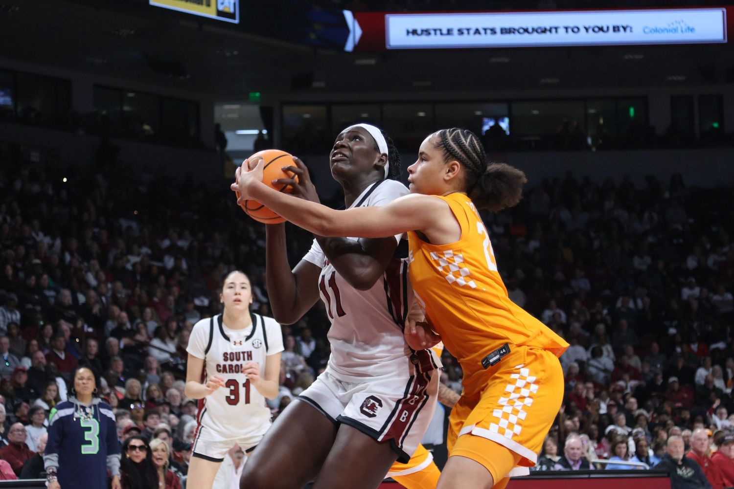 South Carolina basketball player secures the ball while a Tennessee defender reaches across her.