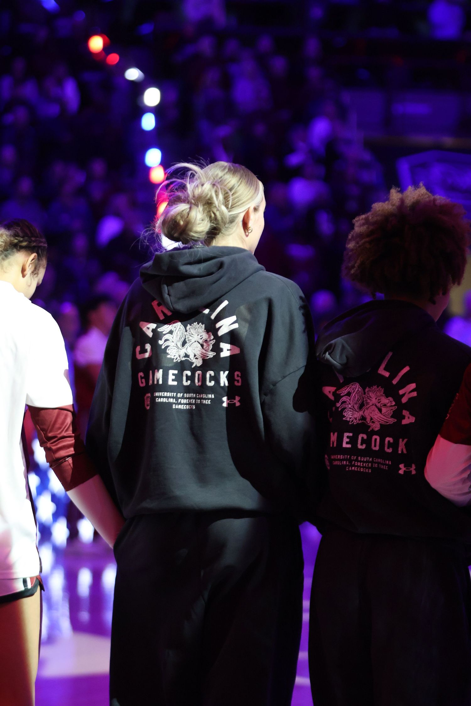South Carolina women's basketball players stand together under purple pregame lights.