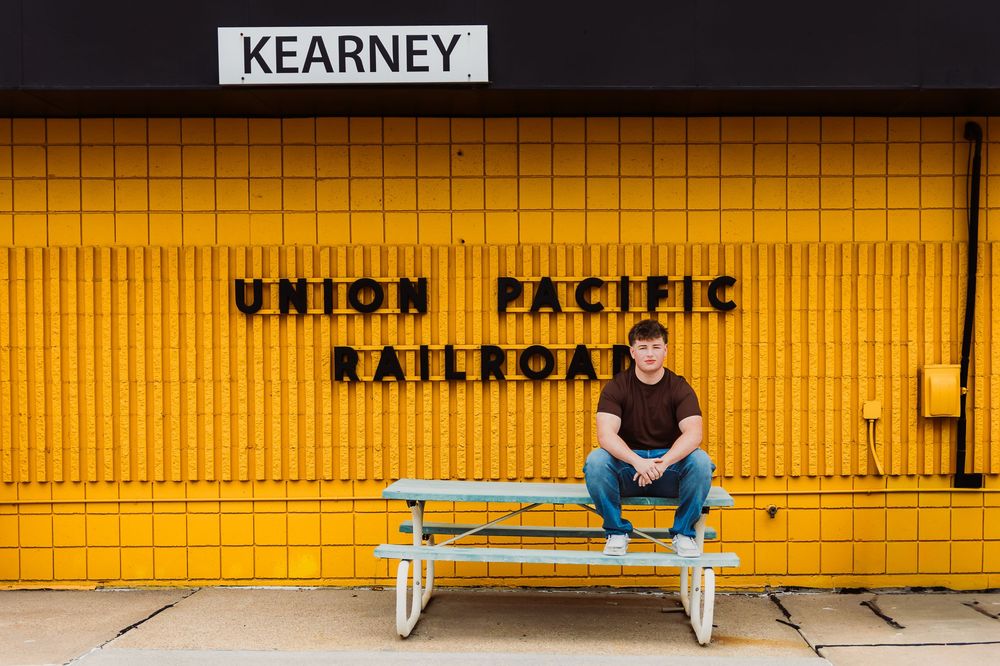 Person sitting on bench at Kearney Union Pacific Railroad station, yellow tiled wall background.