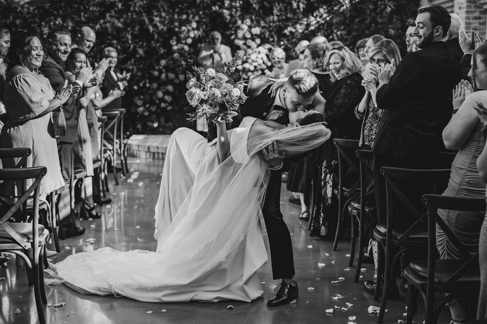 Wedding couple shares a romantic dance surrounded by guests throwing confetti during an outdoor celebration.