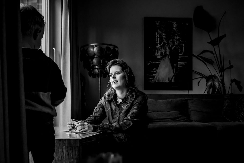 Woman sitting at table in moody black and white living room photo.