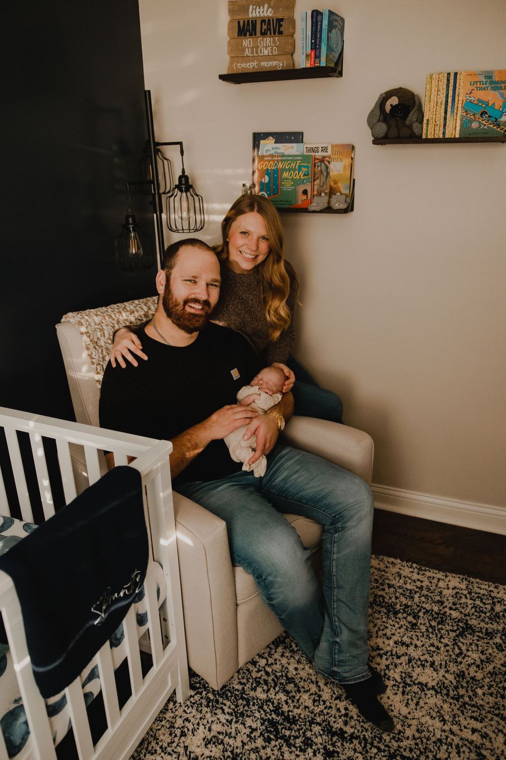Family relaxing together in nursery with bookshelves and modern decor.