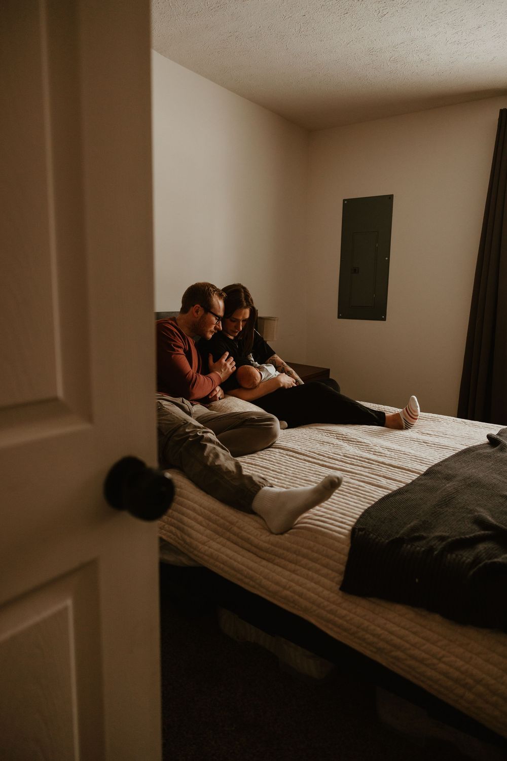 A sequence of intimate moments captured in a dimly lit bedroom showing two people resting together on a mattress.