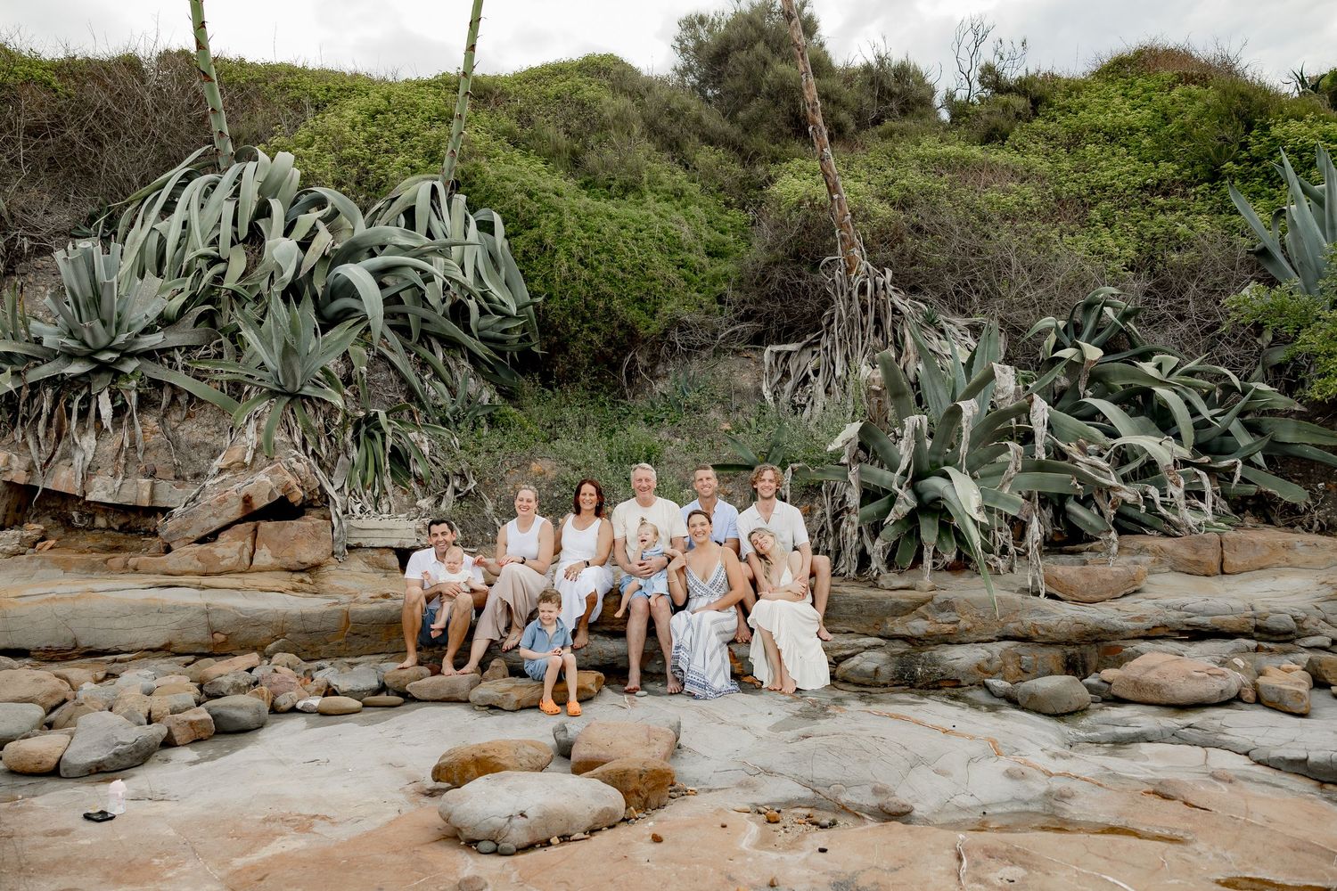Family group photo under blooming cherry blossom trees in a garden setting.