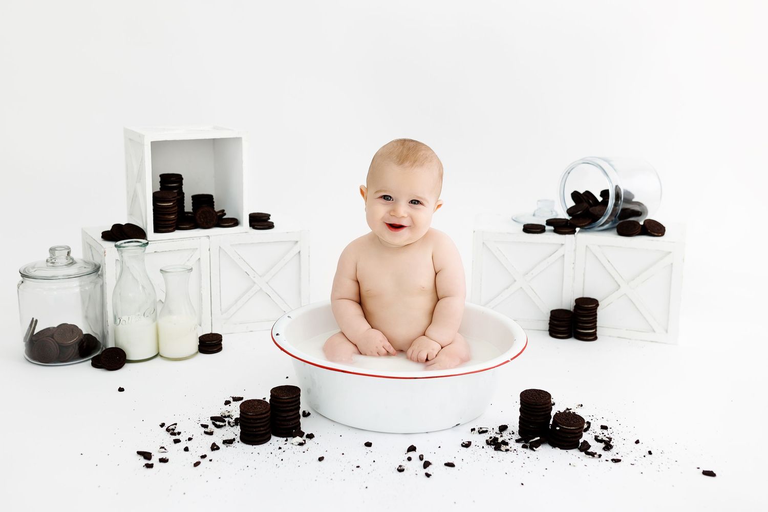 Vintage metal basin with floral decorations used for baby photography against white background.