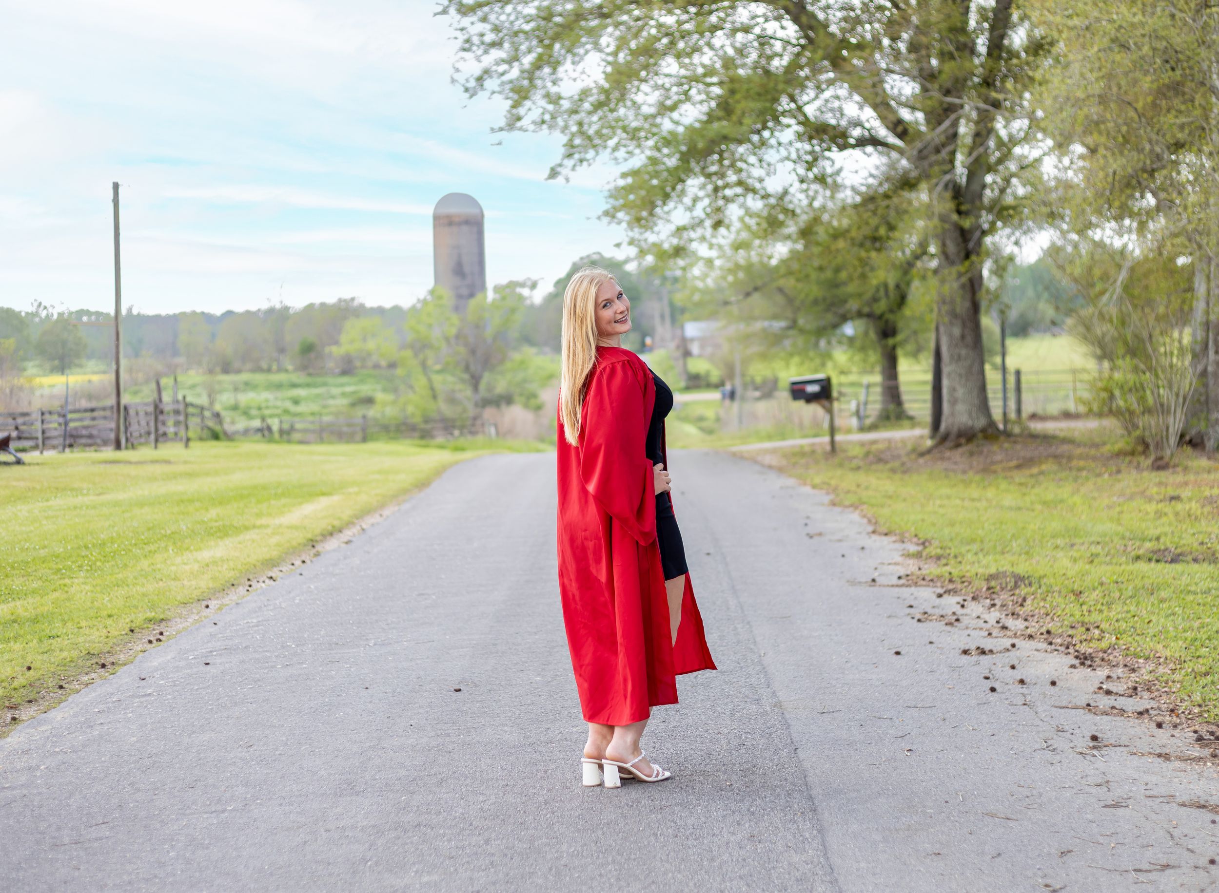 A person in a red coat walks along a winding path through a green park on a cloudy day.