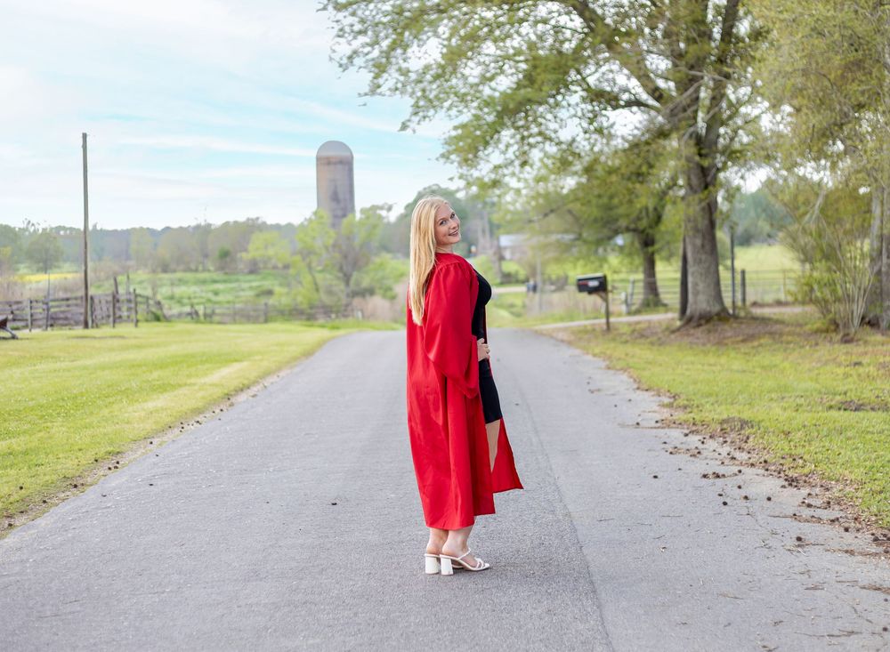 A person in a red coat walks along a winding path through a green park on a cloudy day.