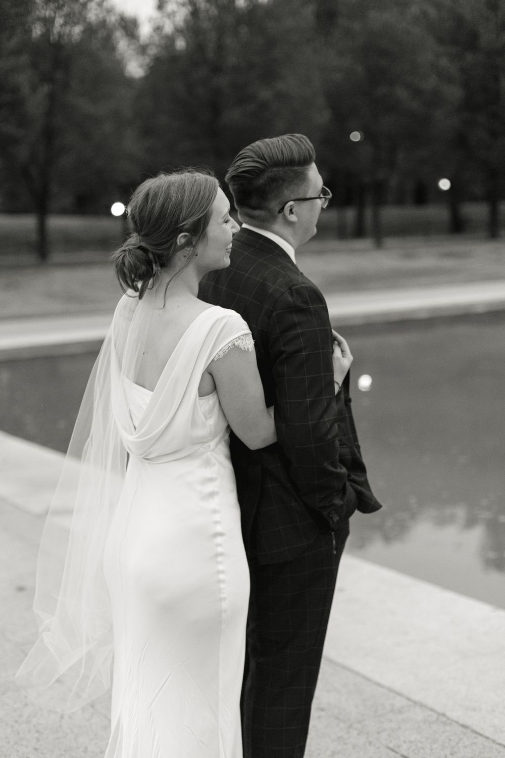 Black and white photo of bride and groom standing back to back by the Reflecting Pool.