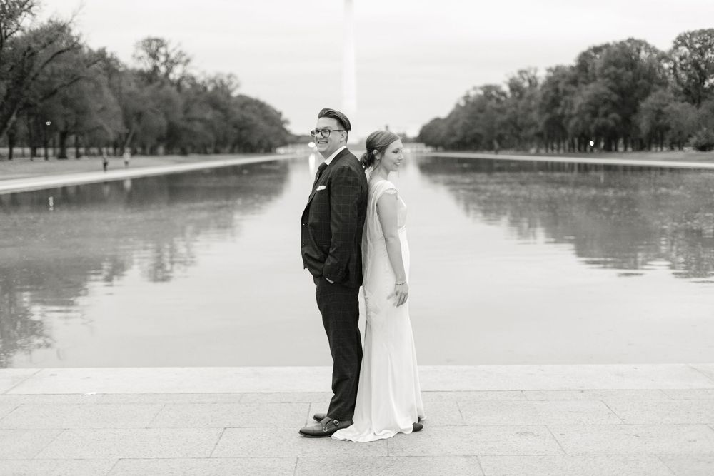Black and white portrait of bride and groom standing together at the National Mall Reflecting Pool.