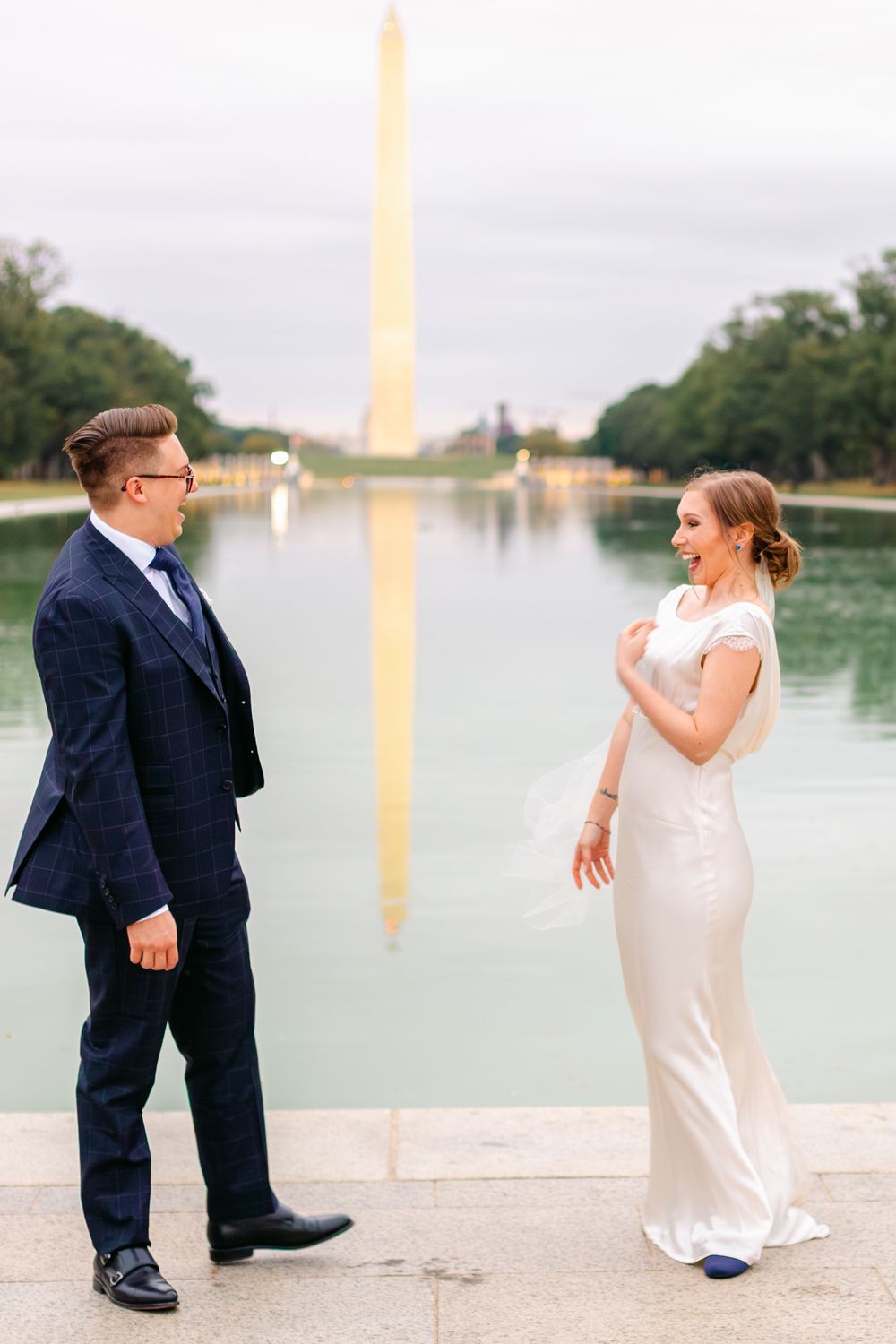 Bride and groom share a joyful moment by the Reflecting Pool with Washington Monument backdrop.