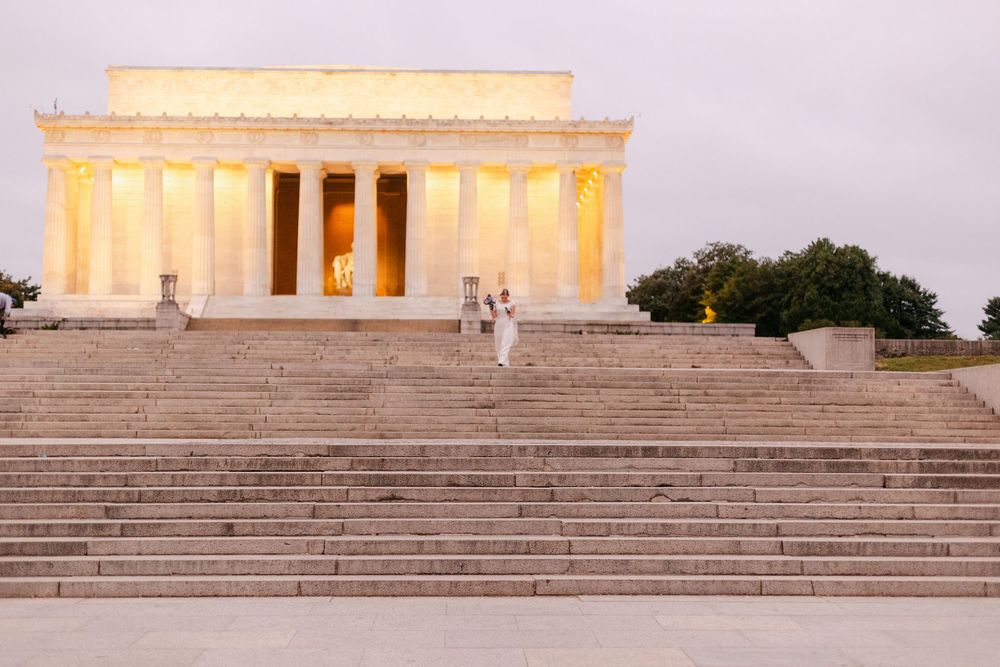 Couple poses on the illuminated steps of the Lincoln Memorial at dawn in Washington DC.