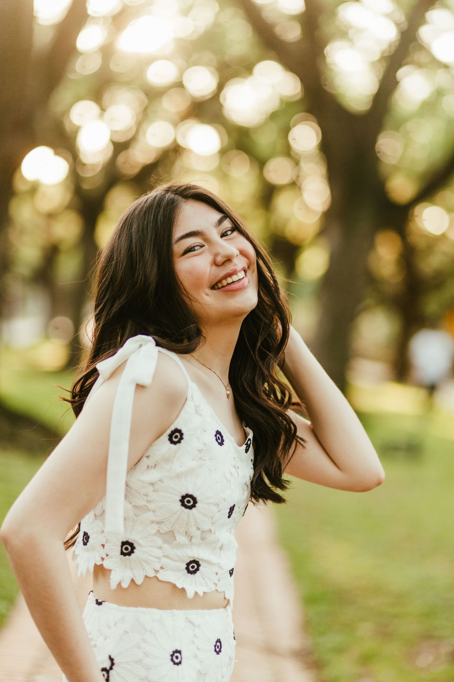 A girl smiles over her shoulder at her STL photographer in a sunny wooded area.