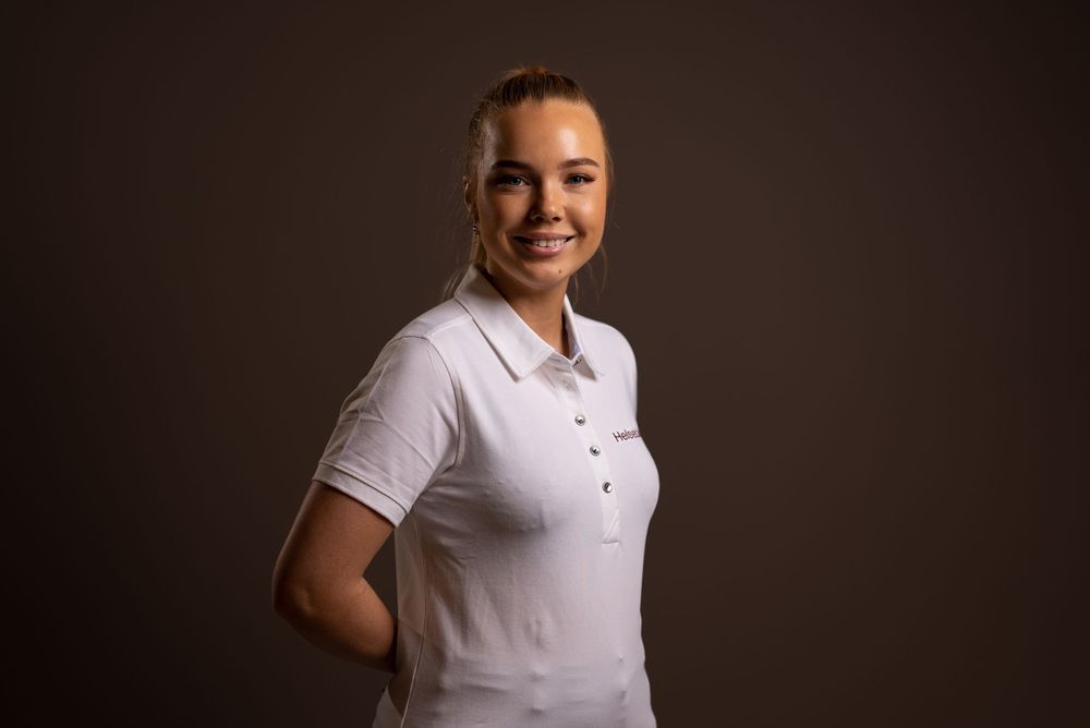 Business casual portraits with person in white polo against neutral backdrop.