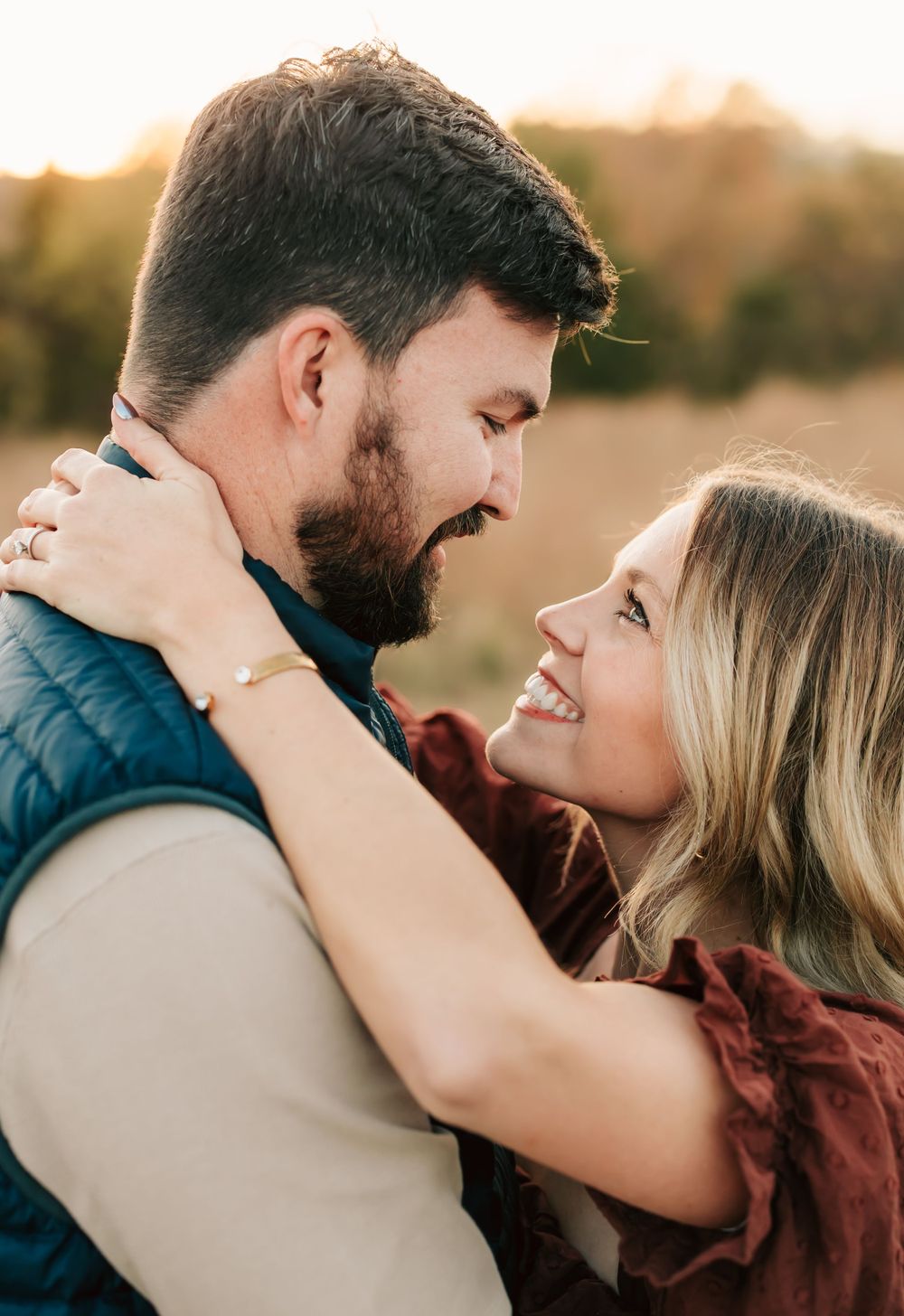 A couple embraces in a loving moment during golden hour sunset with warm autumn lighting creating a romantic atmosphere.