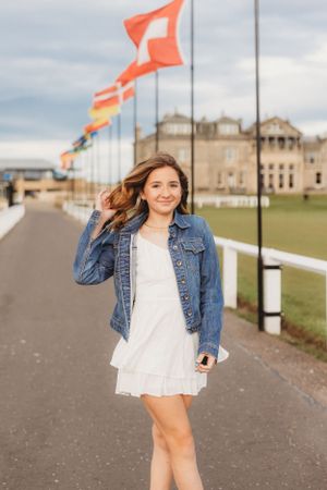 A casual pose on a walkway with orange flags flying in the background.
