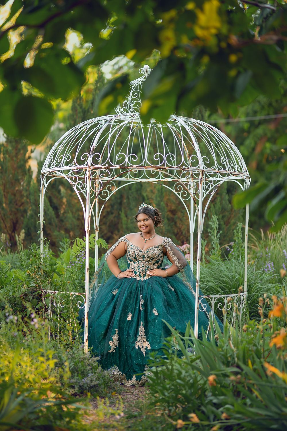 Elegant photoshoot featuring teal gown in garden setting with decorative white metal gazebos.