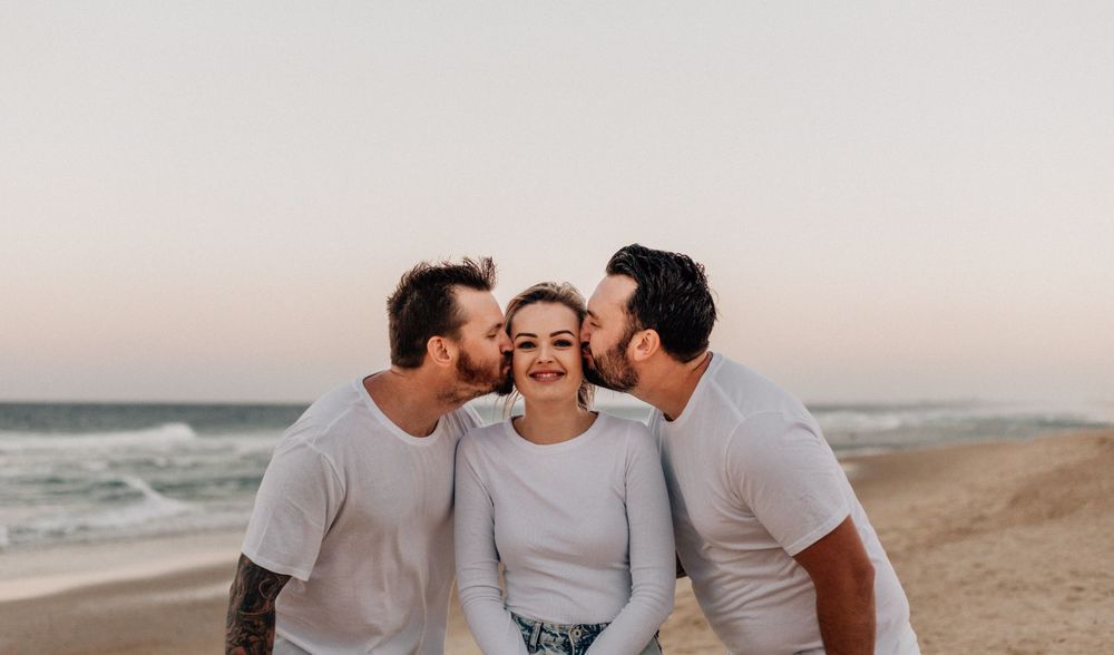 Family sharing loving kisses and embraces during casual beach photoshoot.
