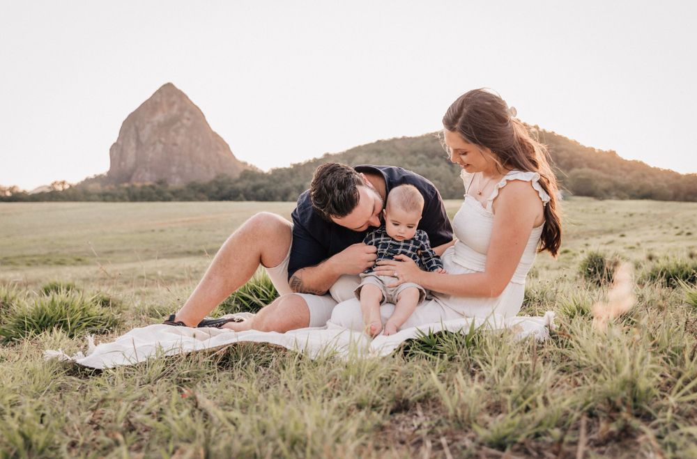 Family lounging on grass with distinctive mountain peak in background.
