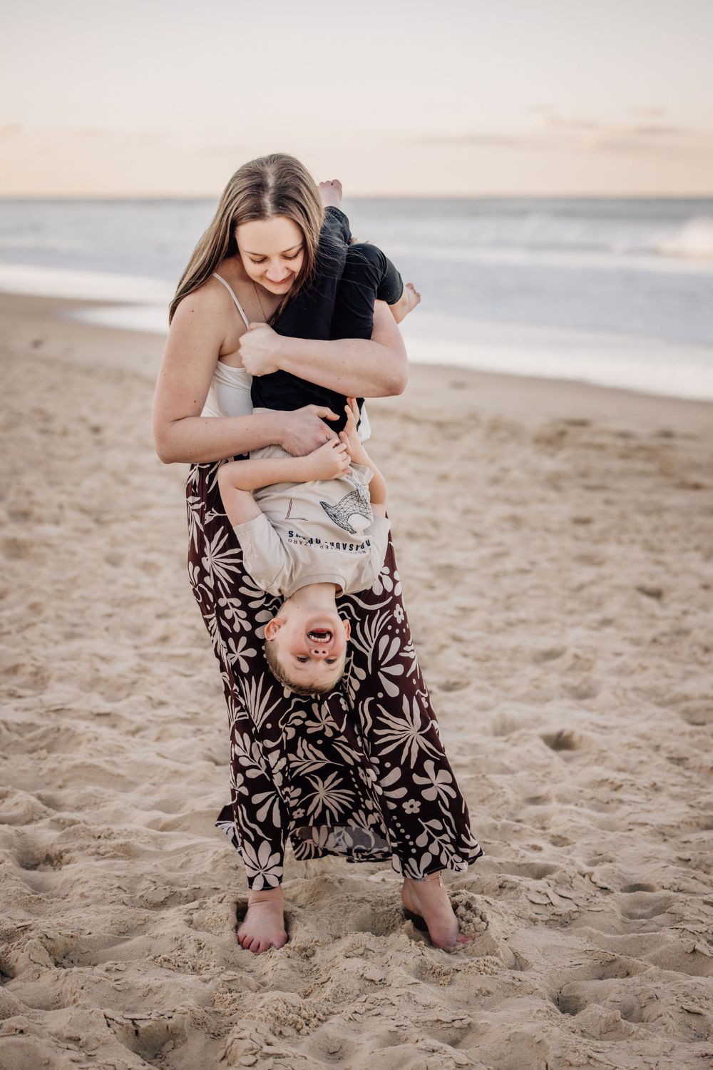 Sweet beach moments as parent and child play together in the sand during golden hour.