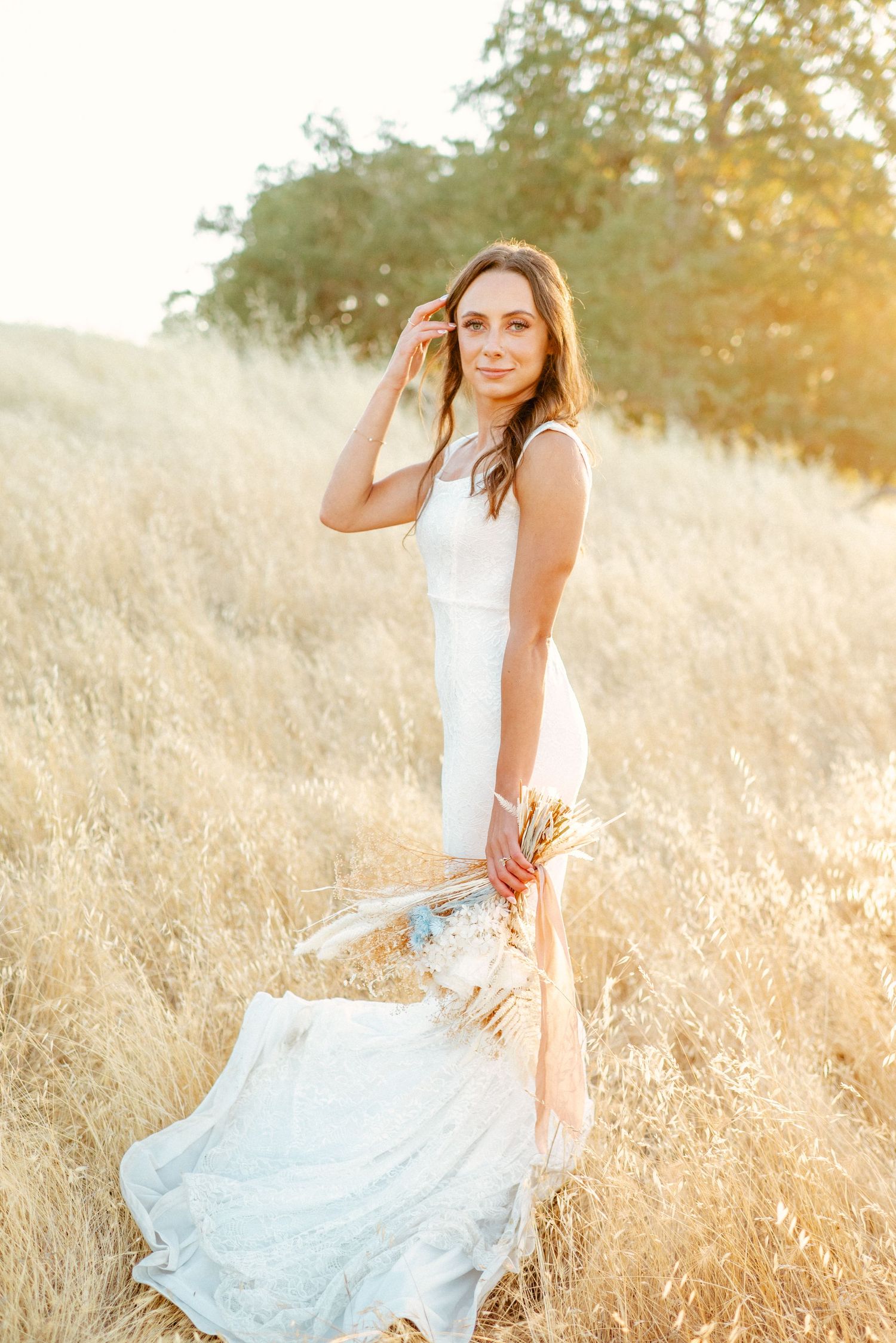 Woman in white dress twirling in golden sunlit field.