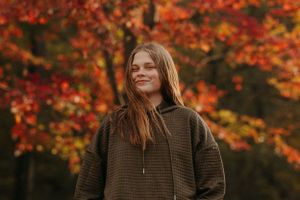 Fall portrait with vibrant orange and red autumn foliage in the background.