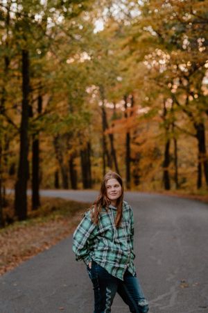 Portrait on winding forest road surrounded by golden autumn trees.