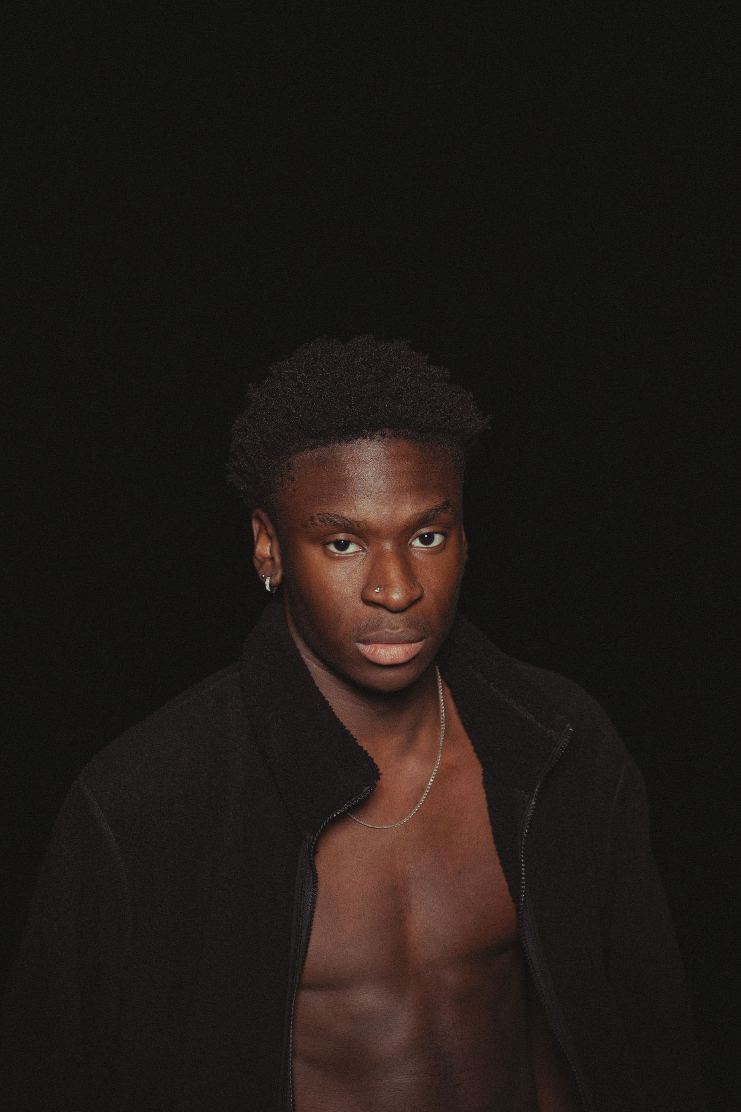 Fashion portrait in dark lighting wearing black jacket.