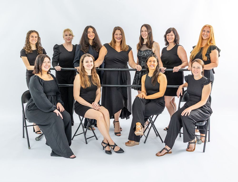 A group of people wearing black outfits pose together in a modern studio setting for a professional photoshoot.