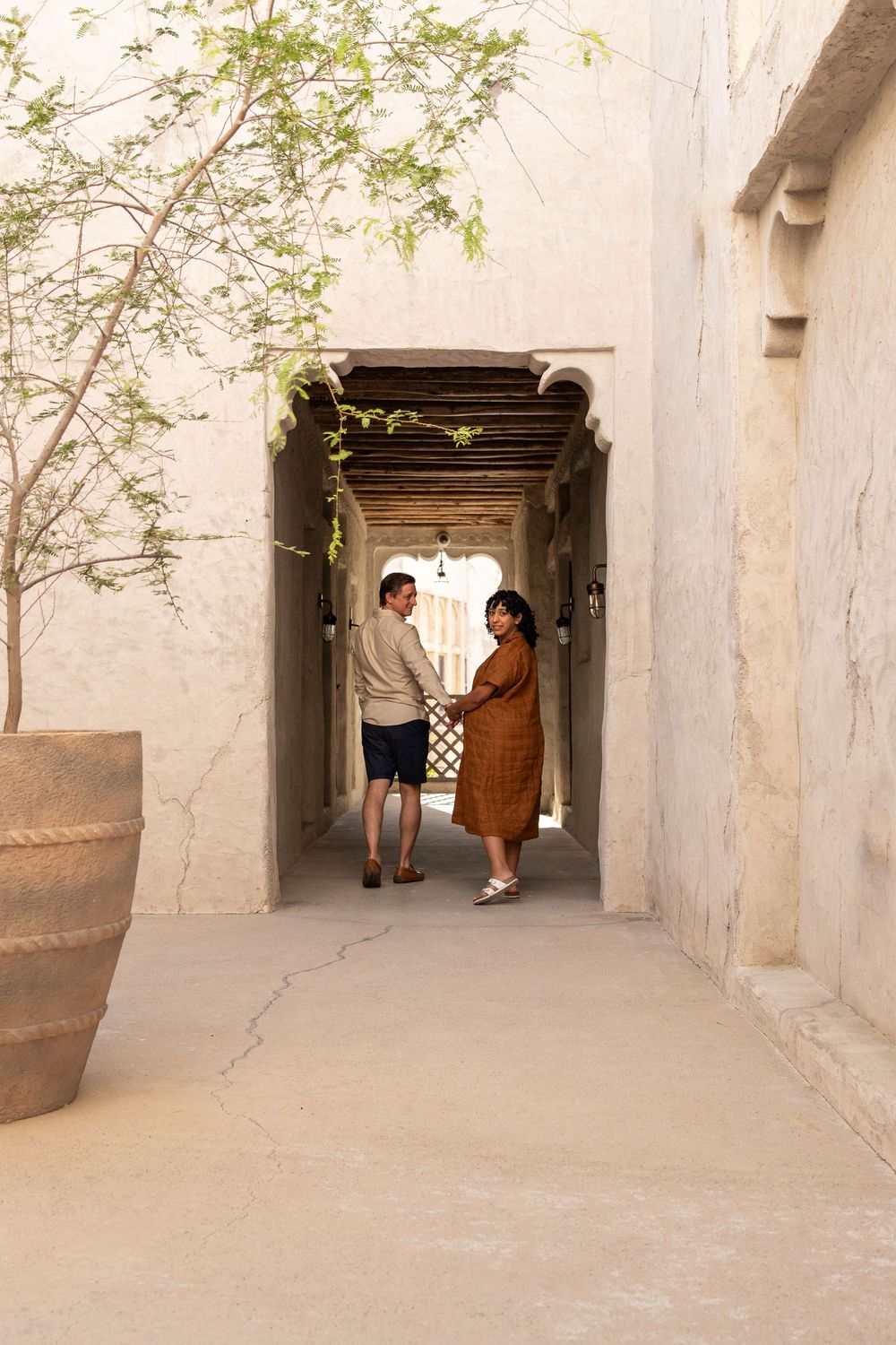 Pregnant woman and husband walking through an arch in old dubai hand in hand during outdoor maternity photo session