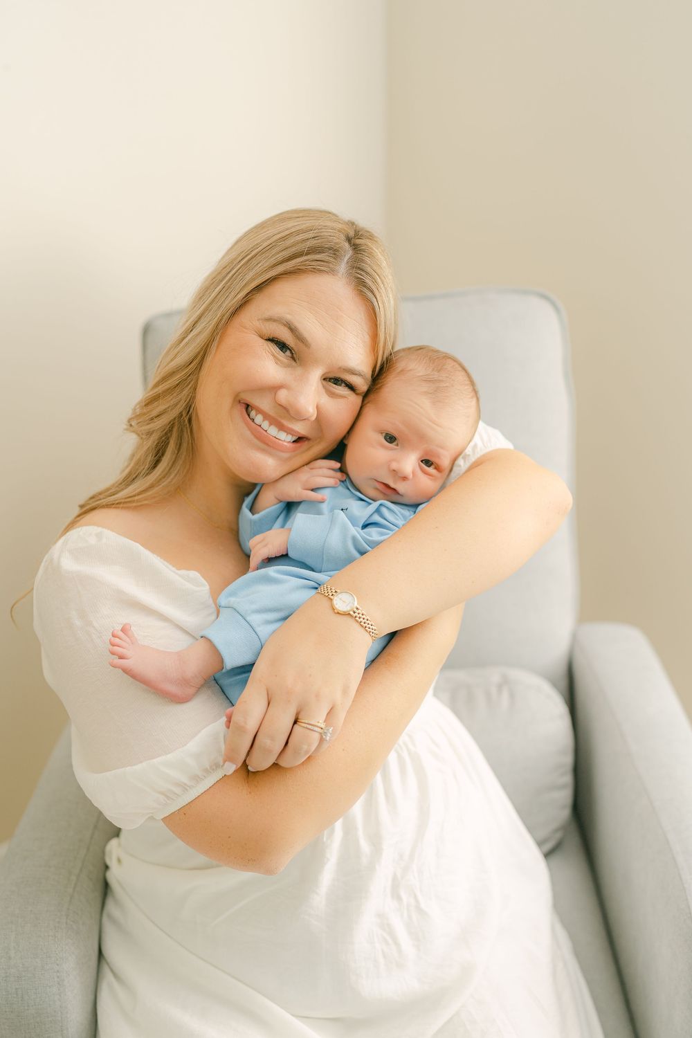 A series of tender moments between parent and newborn baby in light, airy portraits on a gray couch.