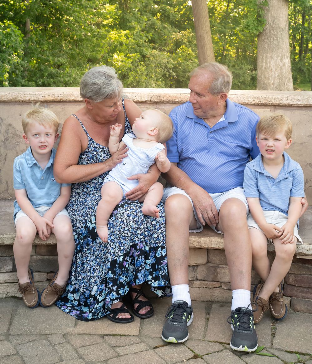 Intimate family moment with grandparents and young grandchildren on stone wall.