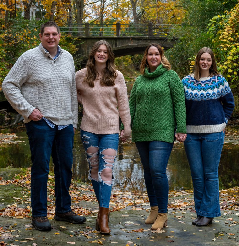 A casual group portrait showing people sitting on wooden steps surrounded by fall foliage.