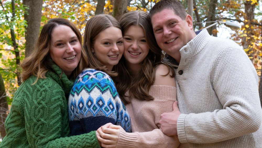 Casual fall family portrait with sweaters and winter hats in autumn foliage.
